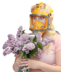 Kvinde med allergi og blomster i hånden har taget gasmaske på