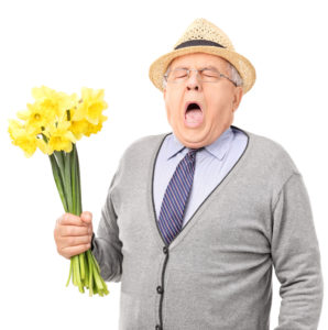 Ældre mand med blomster i hånden nyser